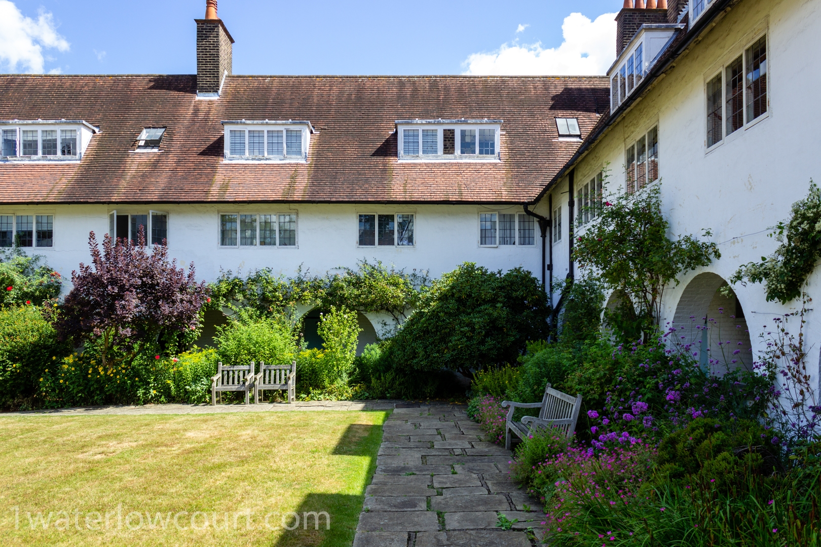 Court yard garden of Waterlow Court, Arts & Crafts Grade II* listed building, M. H. Baillie Scott, 1909. Hampstead Garden Suburb, London NW11 7DT. Flat 1, a one-bedroom, ground-floor flat, is located directly ahead and is for sale. Listed on Rightmove and Zoopla.